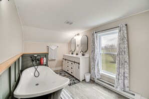 Ein Badezimmer mit einer weißen Badewanne, einem Waschbecken mit Spiegel und einem Fenster mit Vorhang.