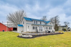 Ein zweistöckiges Haus mit blauem Dach, einer Veranda und einer kleinen Terrasse mit Gartenmöbeln.