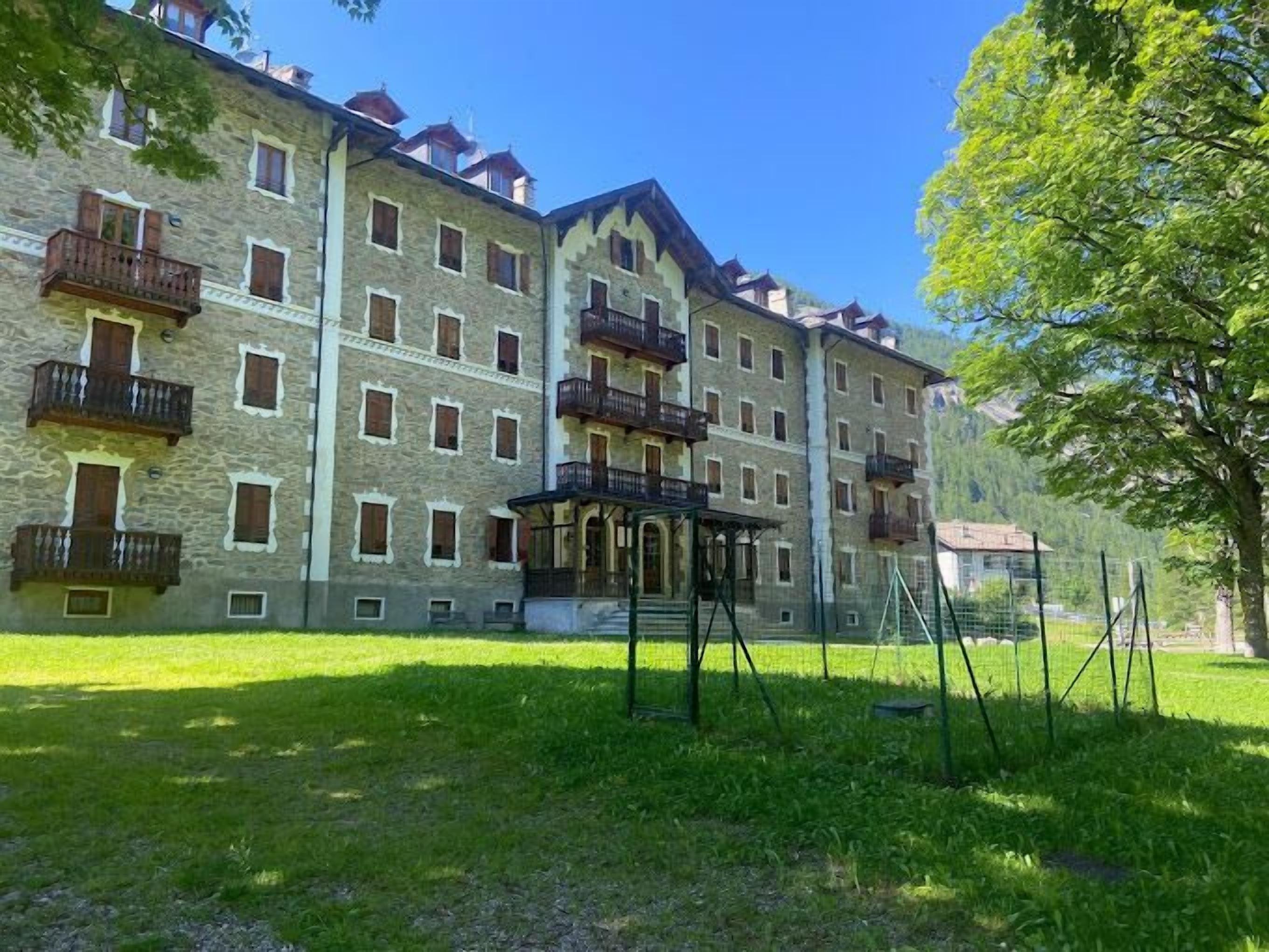 Ein mehrstöckiges Gebäude mit Balkonen, einem überdachten Eingang und einem grünen Innenhof.