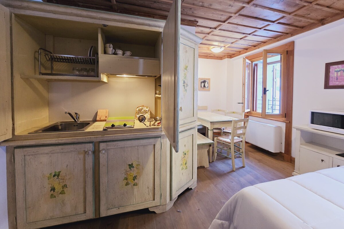 A compact kitchen with a sink, stove, and cabinets. There is a dining area with a table and chairs.