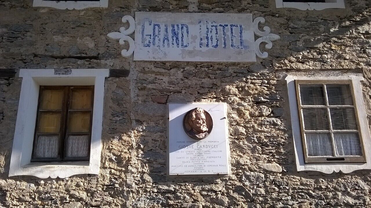 A stone building with a sign reading "GRAND HOTEL" and a plaque with text.