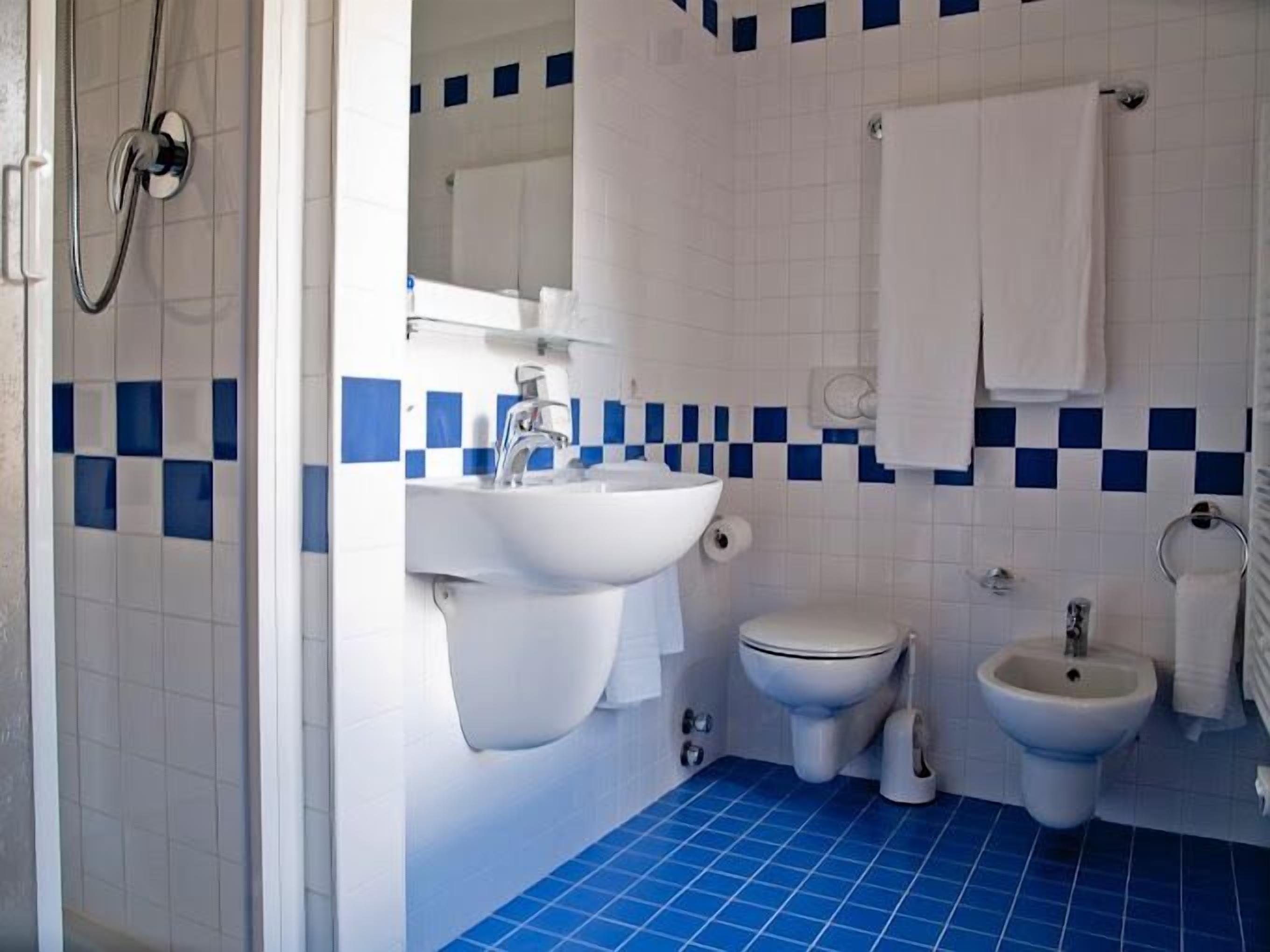 Une salle de bain équipée d’un lavabo, de toilettes, d’un bidet et d’un miroir.