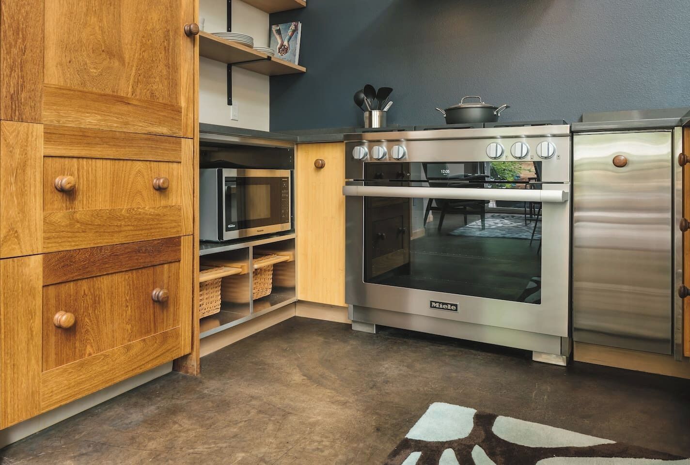 A modern kitchen with wooden cabinetry, a stainless steel oven, and a microwave.
