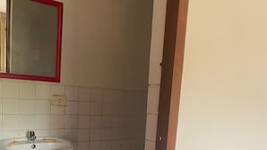 A bathroom with a white sink, a mirror with a red frame, and a toilet.