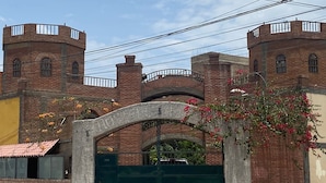 A brick building with a large arched entrance and a green gate.