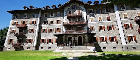 A multi-story stone building with balconies and a central entrance.