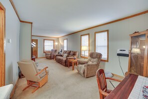 Relax in this spacious living room with a high ceiling, featuring a variety of seating options and a dining table.