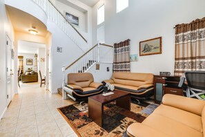 Ein großzügiger Wohnraum mit Treppe, Ledersofas, einem Couchtisch und einem Schreibtisch.