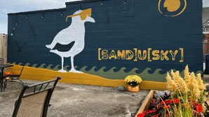 A mural of a seagull on a wall with the text "[SAND] [SKY]" and a small yellow circle. - Private 3-Bdrm Unit. Historic Home, Downtown Sandusky. Family friendly! (Sandusky)
