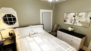 A neatly arranged bedroom with a bed, bedside table, chair, dresser, and artwork on the wall. - Private 3-Bdrm Unit. Historic Home, Downtown Sandusky. Family friendly! (Sandusky)