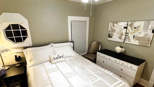 A neatly arranged bedroom with a bed, bedside table, chair, dresser, and artwork on the wall. - Private 3-Bdrm Unit. Historic Home, Downtown Sandusky. Family friendly! (Sandusky)