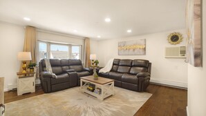 Ein modernes Wohnzimmer mit zwei Ledersofas, einem Couchtisch und einem großen Fenster.