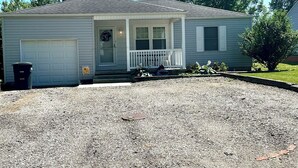 A single-story house with a front porch, a garage, and a small front yard. - Cardinal Cottage - 2 bedroom cozy home (Muncie)