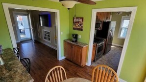 A spacious kitchen with wooden cabinets, a dining area with a table and chairs, and a view into the living room. - Cardinal Cottage - 2 bedroom cozy home (Muncie)