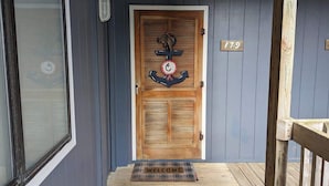 A wooden door with a welcome mat, a number plaque, and a window with blinds. - Toes In The Sand (North Topsail Beach)