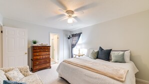 Ein Schlafzimmer mit einem Bett, einem Schminktisch, einem Deckenventilator und einer Tür.