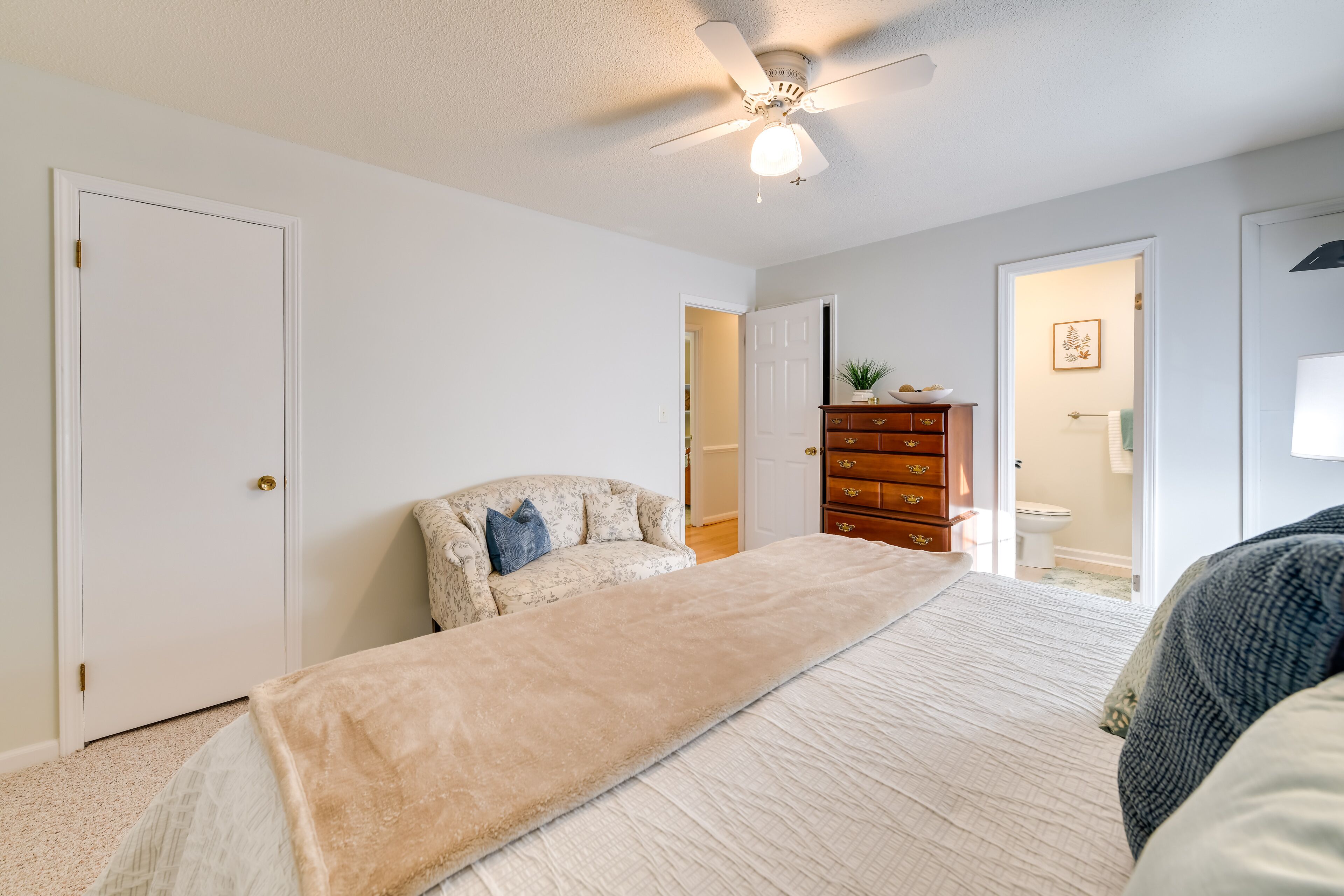 A bedroom with a bed, a dresser, and a ceiling fan.
