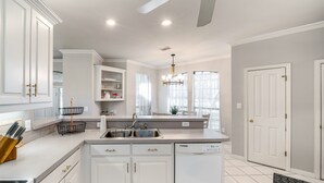 Une cuisine moderne avec des meubles blancs, un lave-vaisselle encastré et un grand îlot central doté d’un évier.