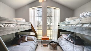 Une chambre avec deux lits superposés, une petite table en bois et une fenêtre avec des rideaux.