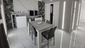 Eine moderne Küche mit Marmor-Spritzschutz, einem integrierten Fernseher und einem Essbereich mit Tisch und Stühlen.