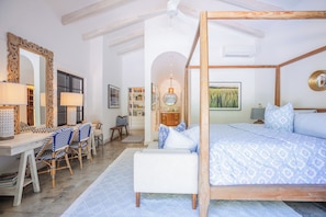 A bedroom with a four-poster bed, a desk with chairs, a bookshelf, and a large mirror.
