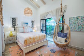 A bedroom with a bed, hanging chair, and a view of the outdoors. - Designer 3 bdr Spanish Style Villa with 25m Lap Pool in the Heart of Guiones. (Nosara)