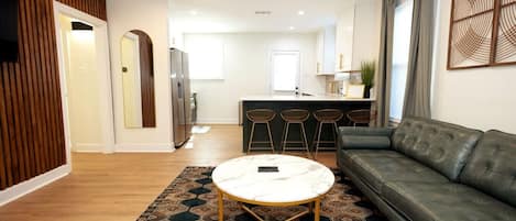A modern living room with a sofa, a coffee table, and a patterned rug.