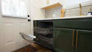 Una cocina equipada con lavavajillas, pileta y ventana con persianas.