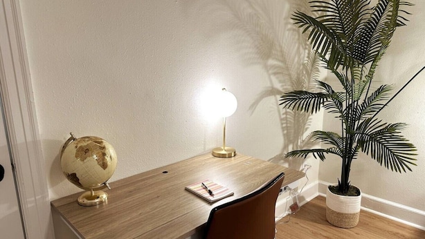 Un escritorio de madera con un globo terráqueo, una lámpara y un cuaderno.