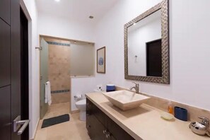 Een moderne badkamer met een grote spiegel, een beige wastafel en een toilet.
