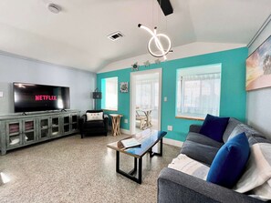 A living room with a TV, a sofa, a coffee table, and teal walls.