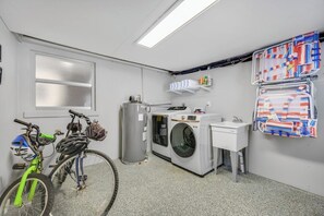 A laundry room with a washing machine, a sink, and a bicycle.