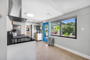 Una cocina moderna con estufa integrada, una ventana con vistas al exterior y una puerta que da a otra habitación.