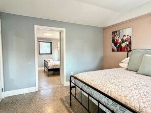 A bedroom with a bed, a chair, and a painting on the wall.