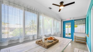 A room with a wooden table, a ceiling fan, and a door leading outside.