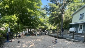 A sandy outdoor area with a basketball hoop, volleyballs, and a water dispenser. - Cottage 5 has a very Hamlin lake cottage feel. More private setting.  (Ludington)