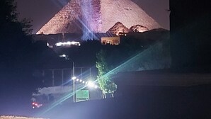 Una pirámide iluminada por rayos de luz en la noche.