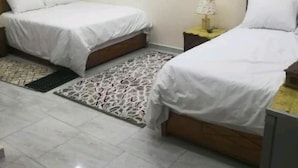 Una habitación de hotel con dos camas, un tapete estampado y una mesita de noche con una lámpara.