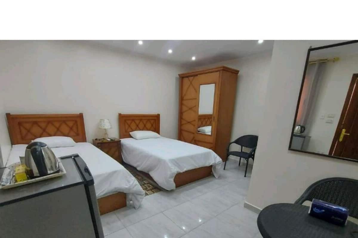 A hotel room with two beds, a wardrobe, a desk, and a chair.