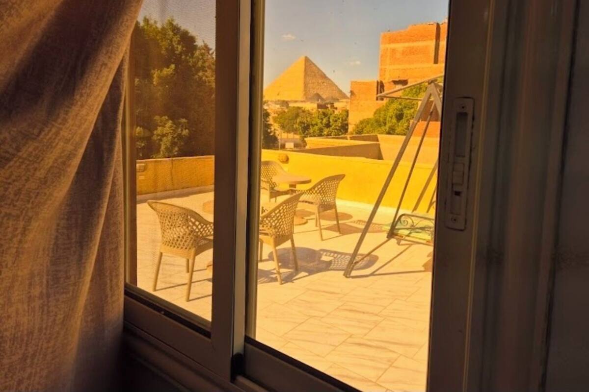 A view from a window overlooking a courtyard with outdoor furniture and a pyramid structure.