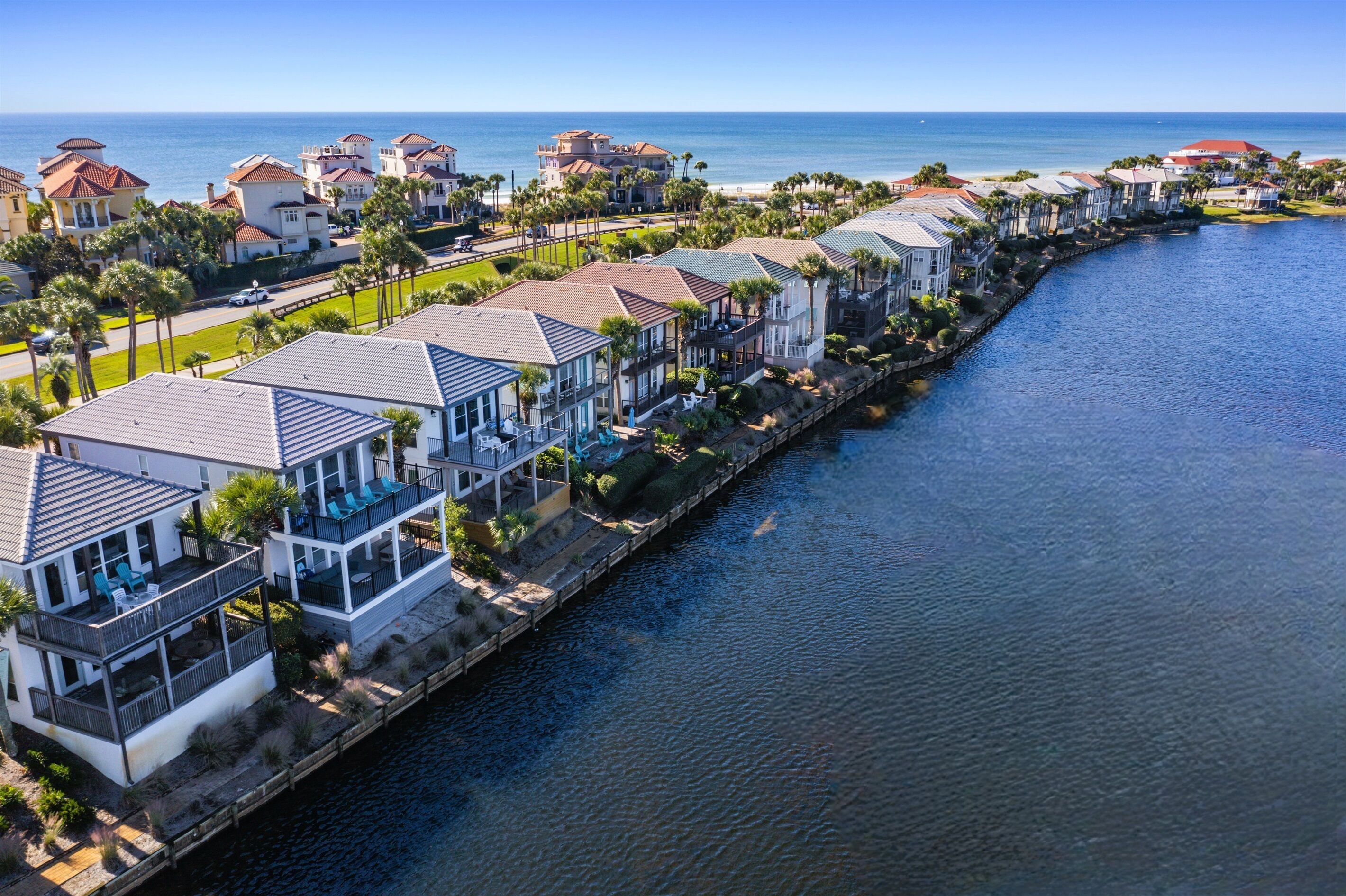 A waterfront residential area with houses along a canal, featuring balconies and views of the ocean.