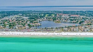Vista aérea de un pueblo costero con playa, un lago y edificios residenciales.