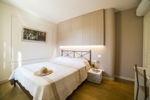 A bedroom with a bed, nightstand, and a wall-mounted light fixture.