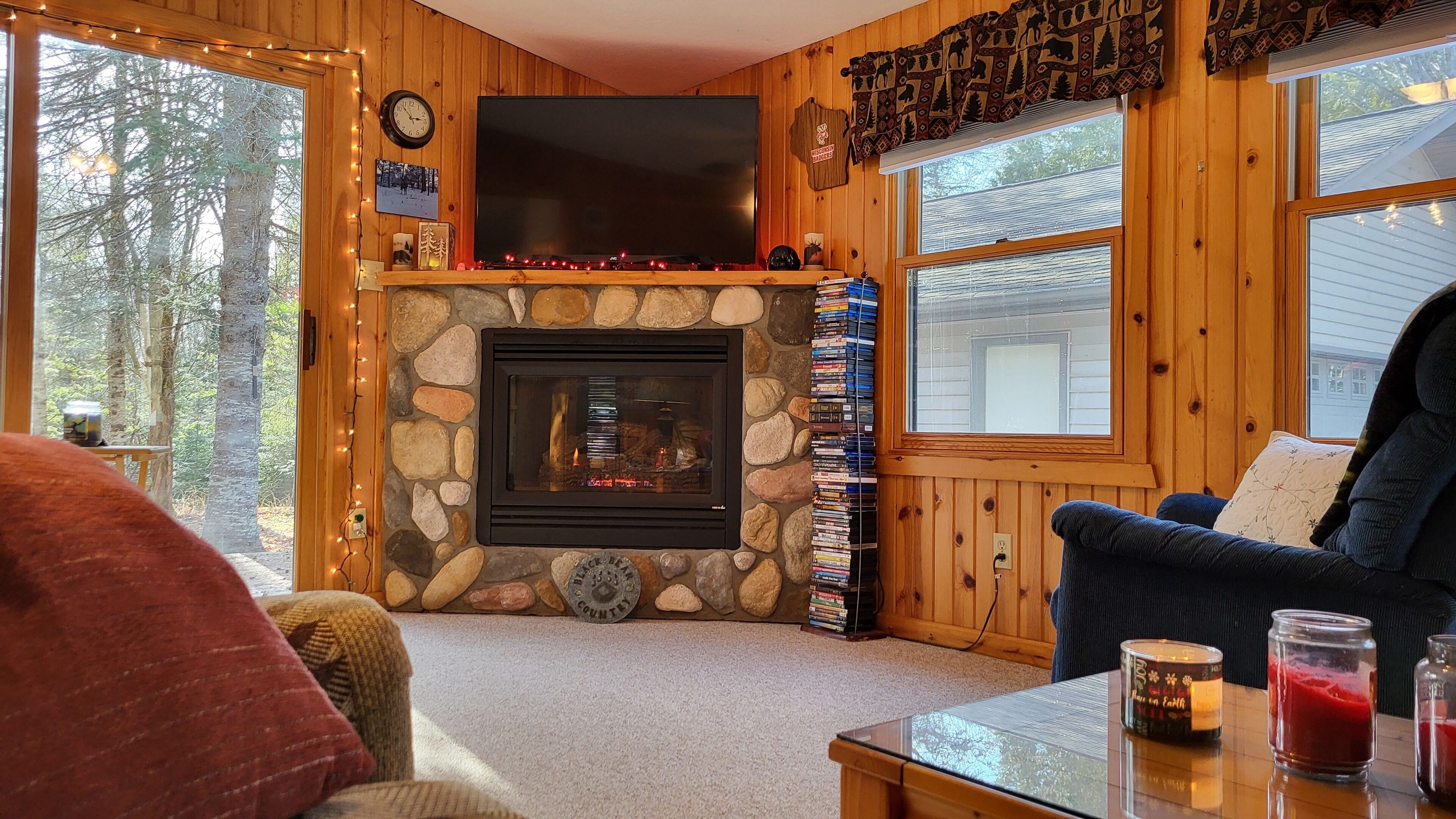 A cozy living room with a stone fireplace, a television mounted above it, and a bookshelf filled with books.