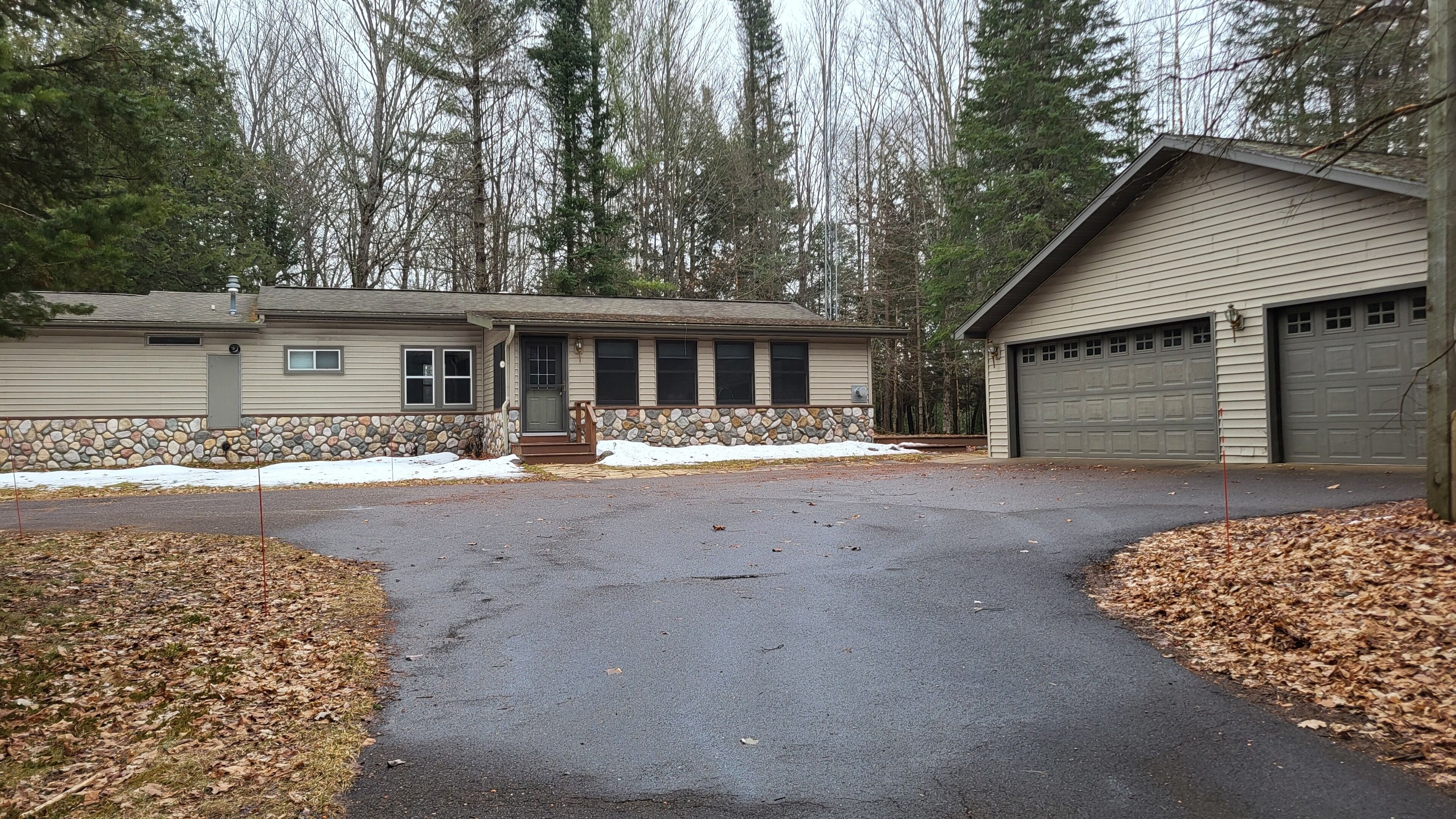 A two-story house with a stone foundation, a garage, and a driveway.