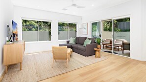 A spacious living area with a sofa, a chair, a coffee table, and a TV on a wooden cabinet. - Southcape, Gerroa by the beach (Gerroa)