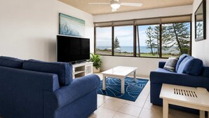 A living room with a flat-screen TV, two sofas, a coffee table, and a ceiling fan. - Bellardoo 12 Beach View Mooloolaba (Mooloolaba)