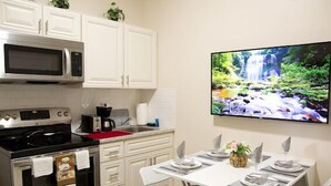 A modern kitchen with white cabinets, a microwave, an oven, and a dining area with a table set for two. - Charming , 2 bedroom , 1 bath  (Kissimmee)