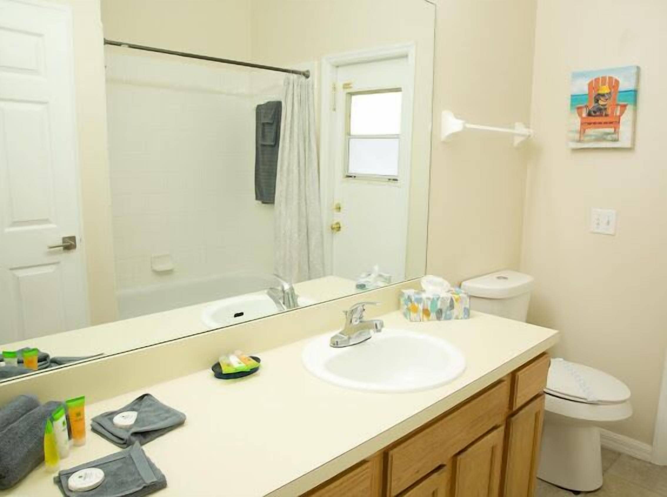 A bathroom with a large mirror, a sink, a toilet, and a shower curtain.