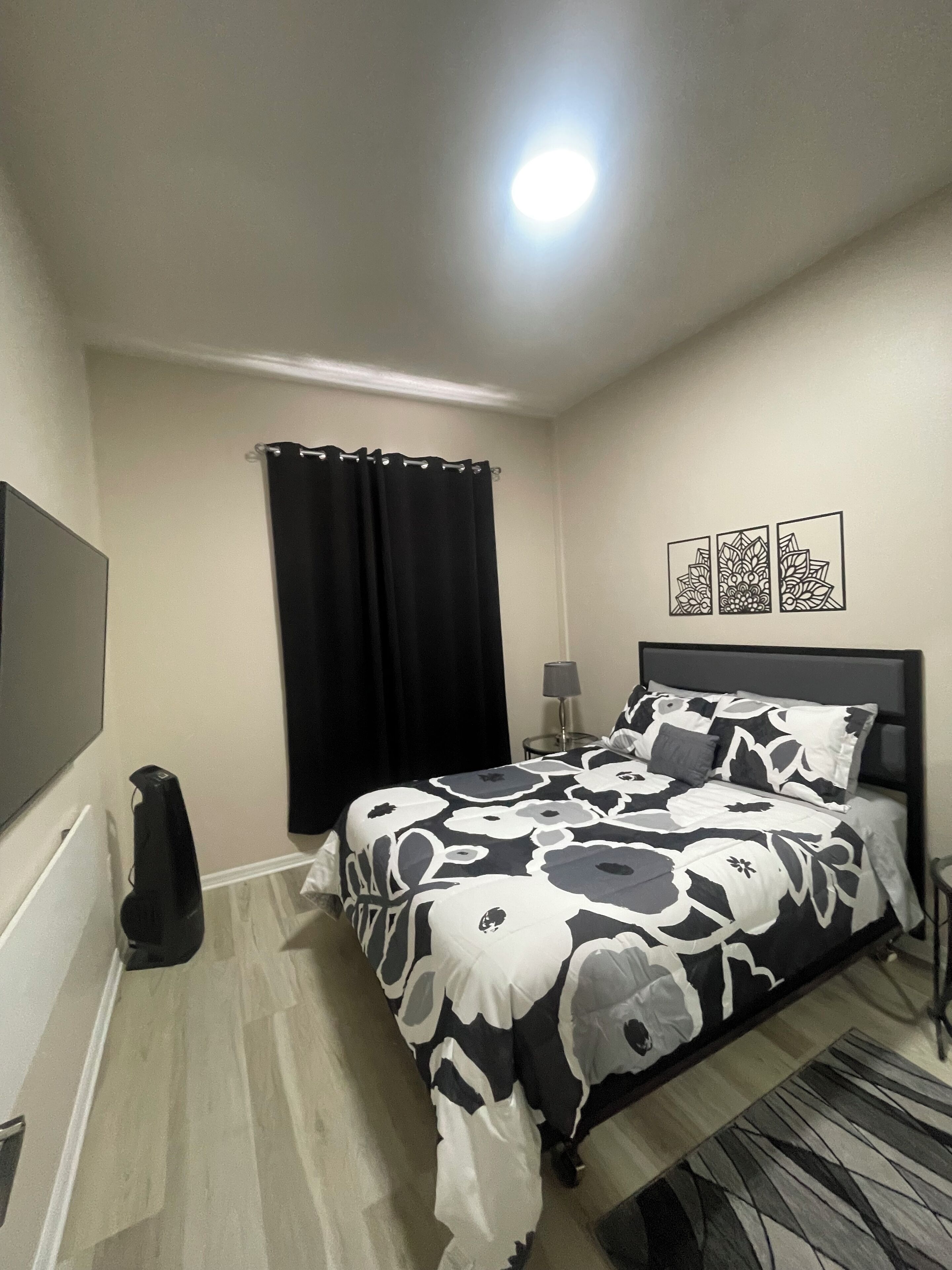 A bedroom with a bed, a TV, a lamp, and a black curtain.